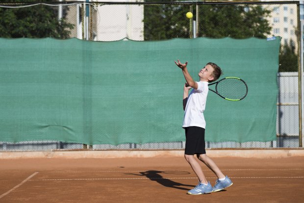 long-shot-kid-serving-tennis-field.jpg